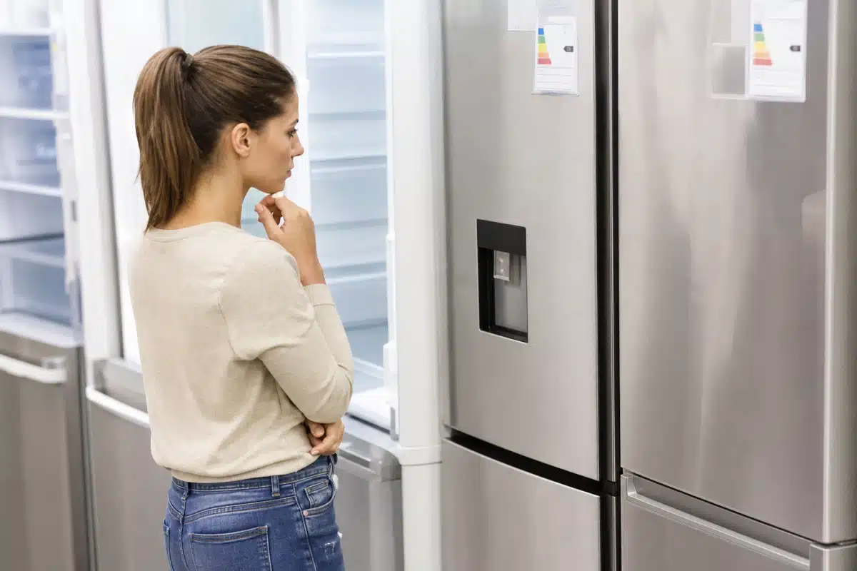 Femme regardant l'intérieur d'un réfrigérateur ouvert